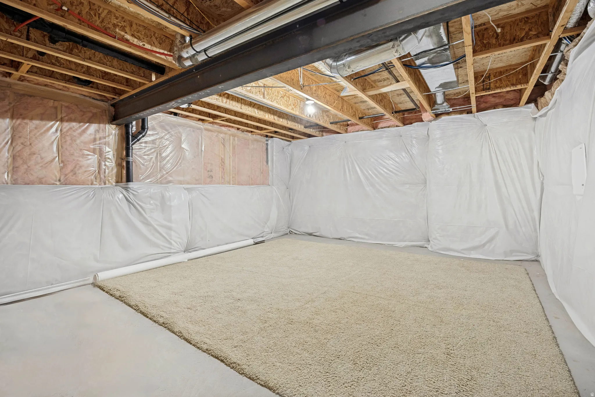 Unfinished basement space featuring exposed wood joists and a steel beam