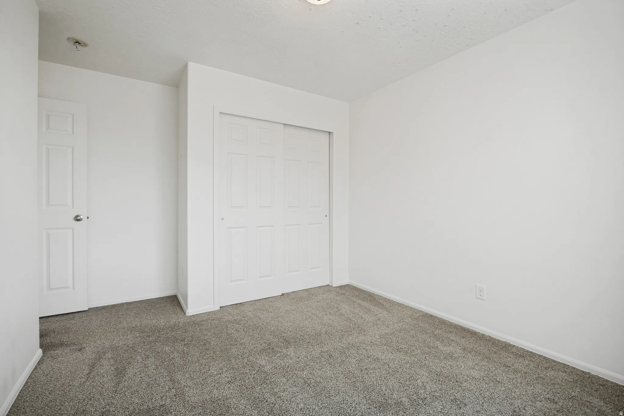 Neutral-toned wall-to-wall carpeting complements the white walls and trim
