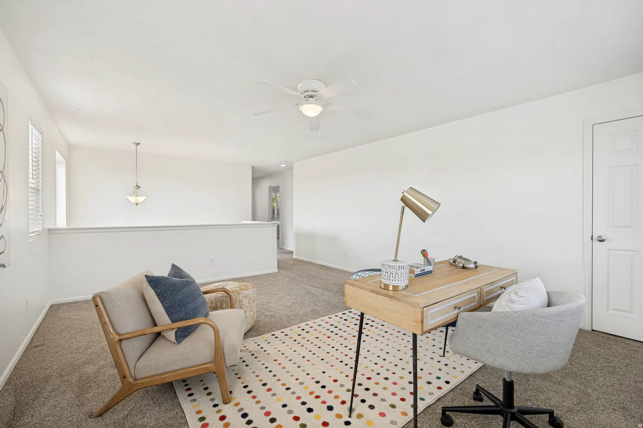 Versatile loft space featuring soft carpet flooring, white walls, and a ceiling fan with integrated lighting
