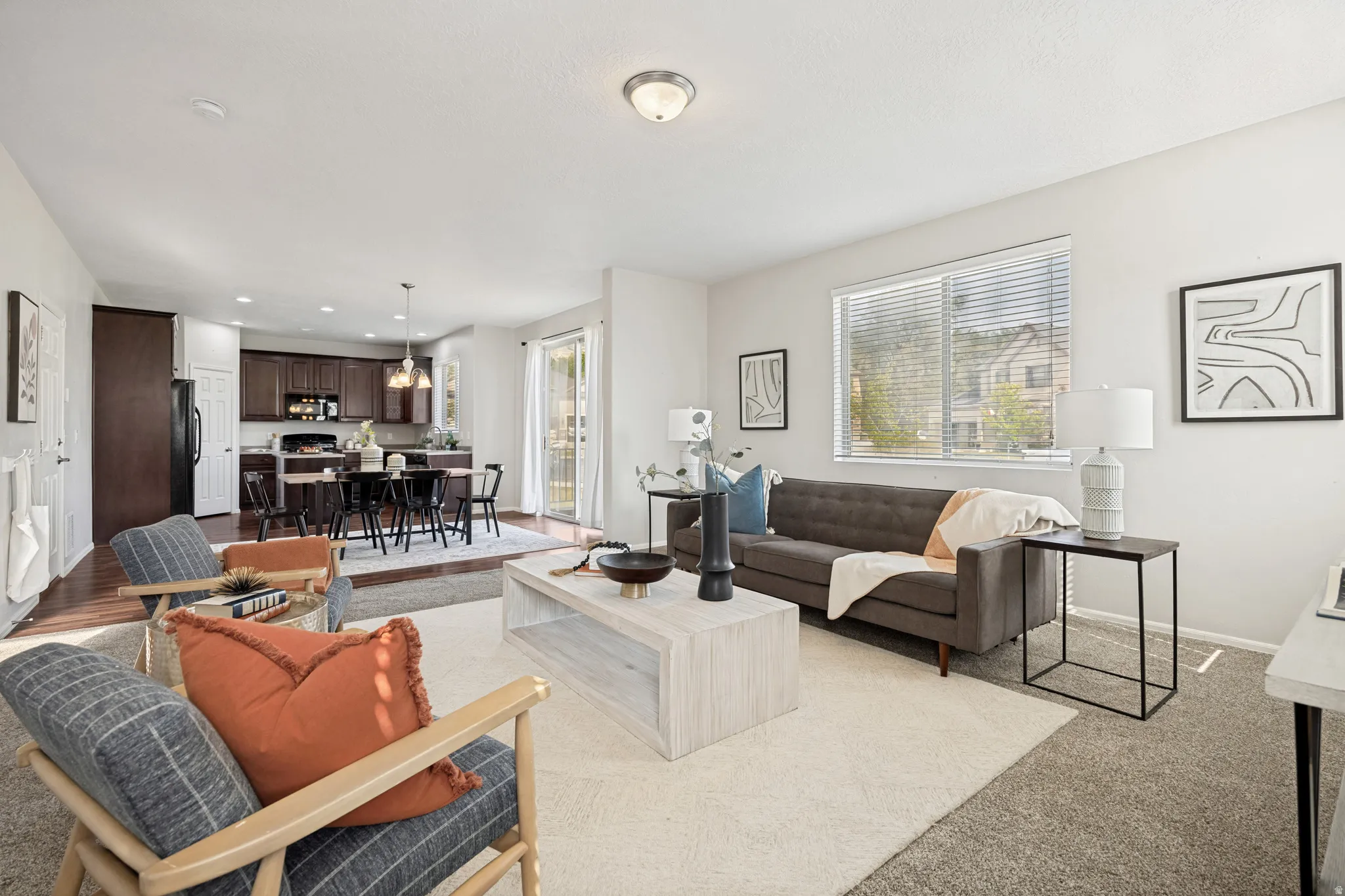 Open-concept living space featuring light-colored walls and a neutral-toned carpet