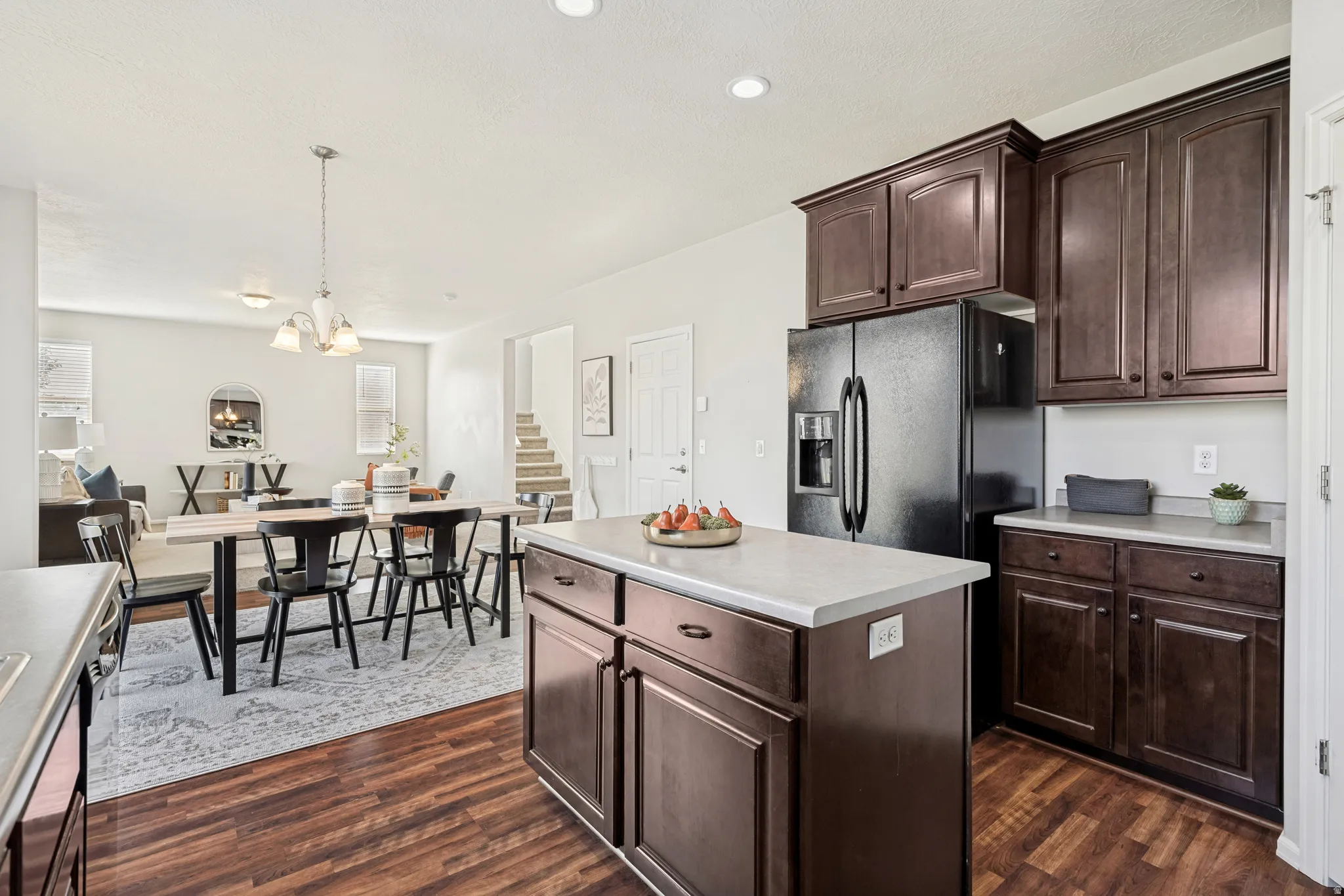 Kitchen island with light-toned countertop, contrasting dark wood-finish cabinetry, and wood-finish flooring