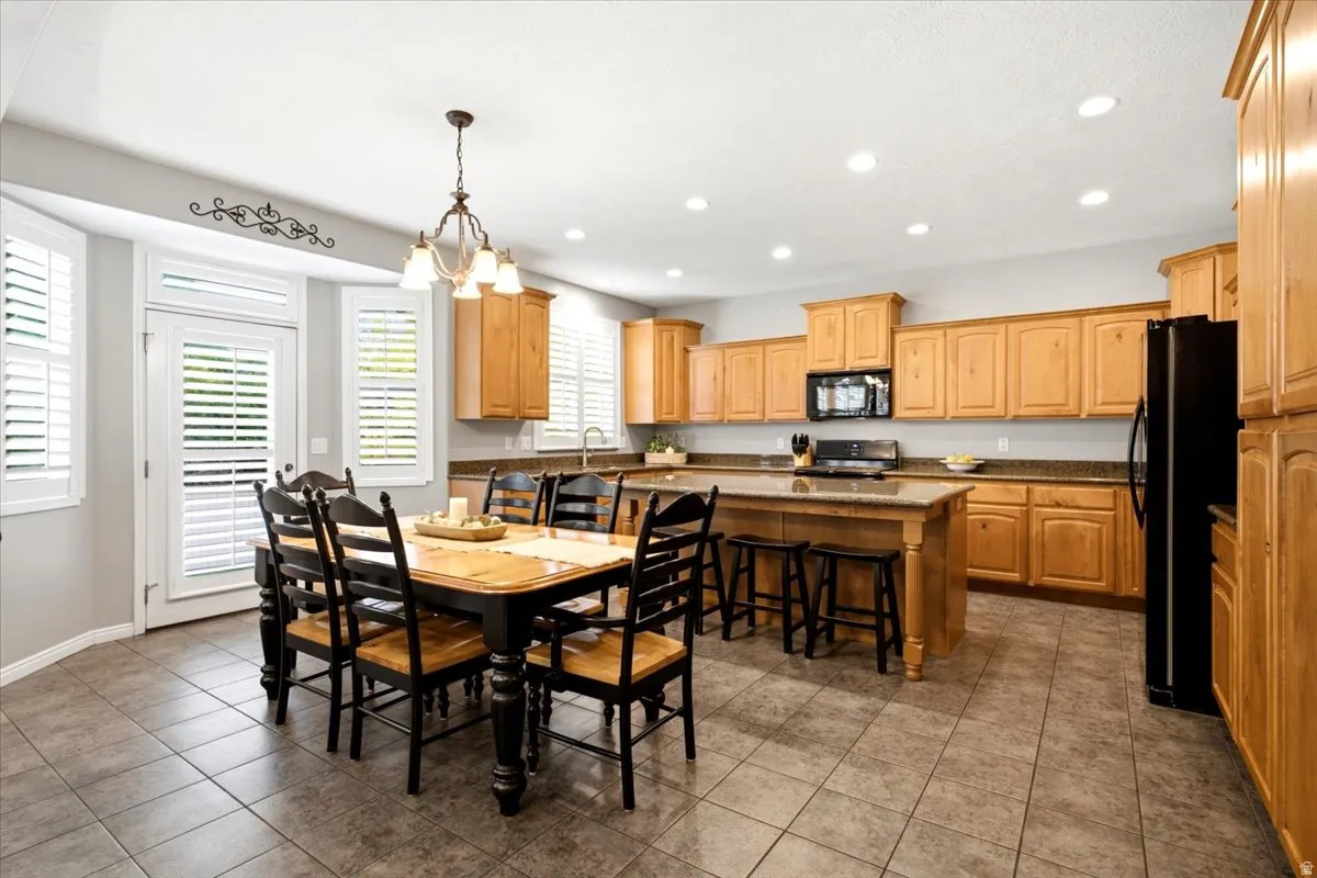 Spacious kitchen featuring light wood cabinetry, stone countertops, and a central island with bar seating