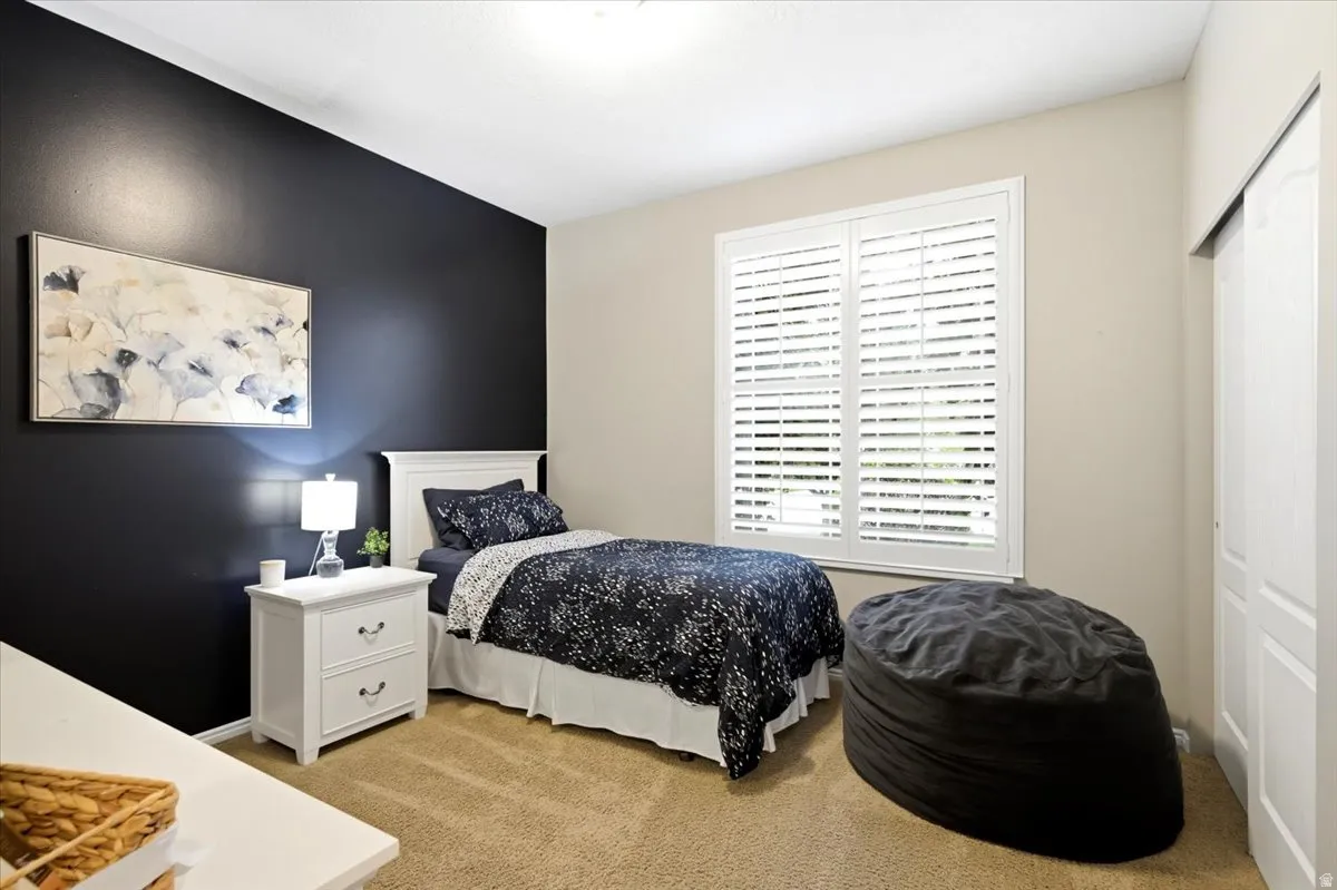 Room featuring a dark accent wall, light-colored walls, white window shutters, and tan carpeting