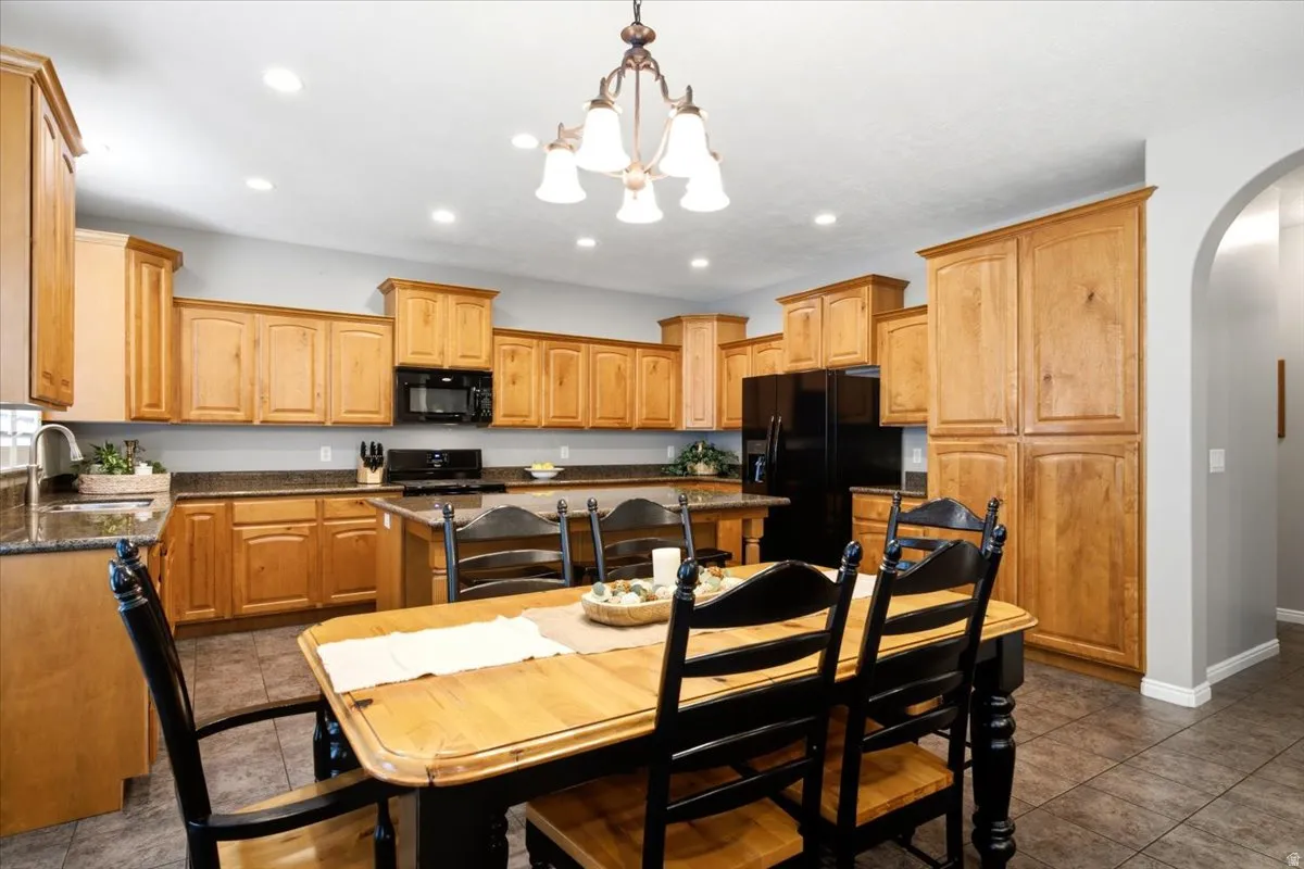 Kitchen featuring abundant cabinetry, dark countertops, built-in black appliances, recessed lighting, and tile flooring