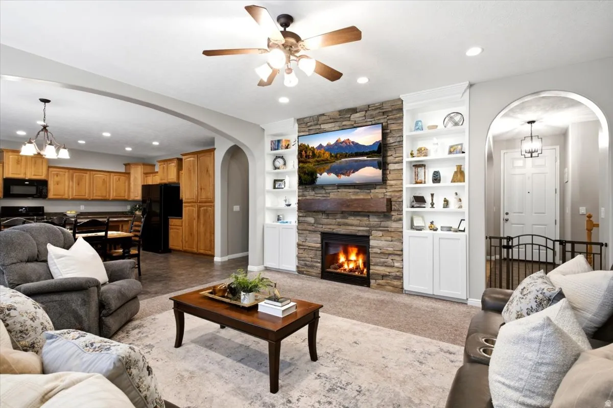 Living area featuring a stone-clad fireplace with a wood mantle, flanked by built-in shelving and lower cabinetry