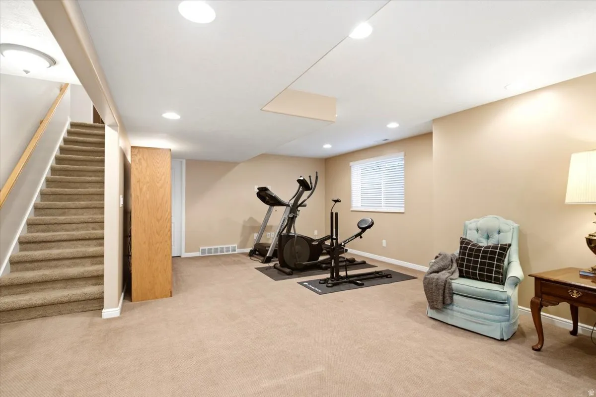 Carpeted room with recessed lighting and a window featuring white blinds