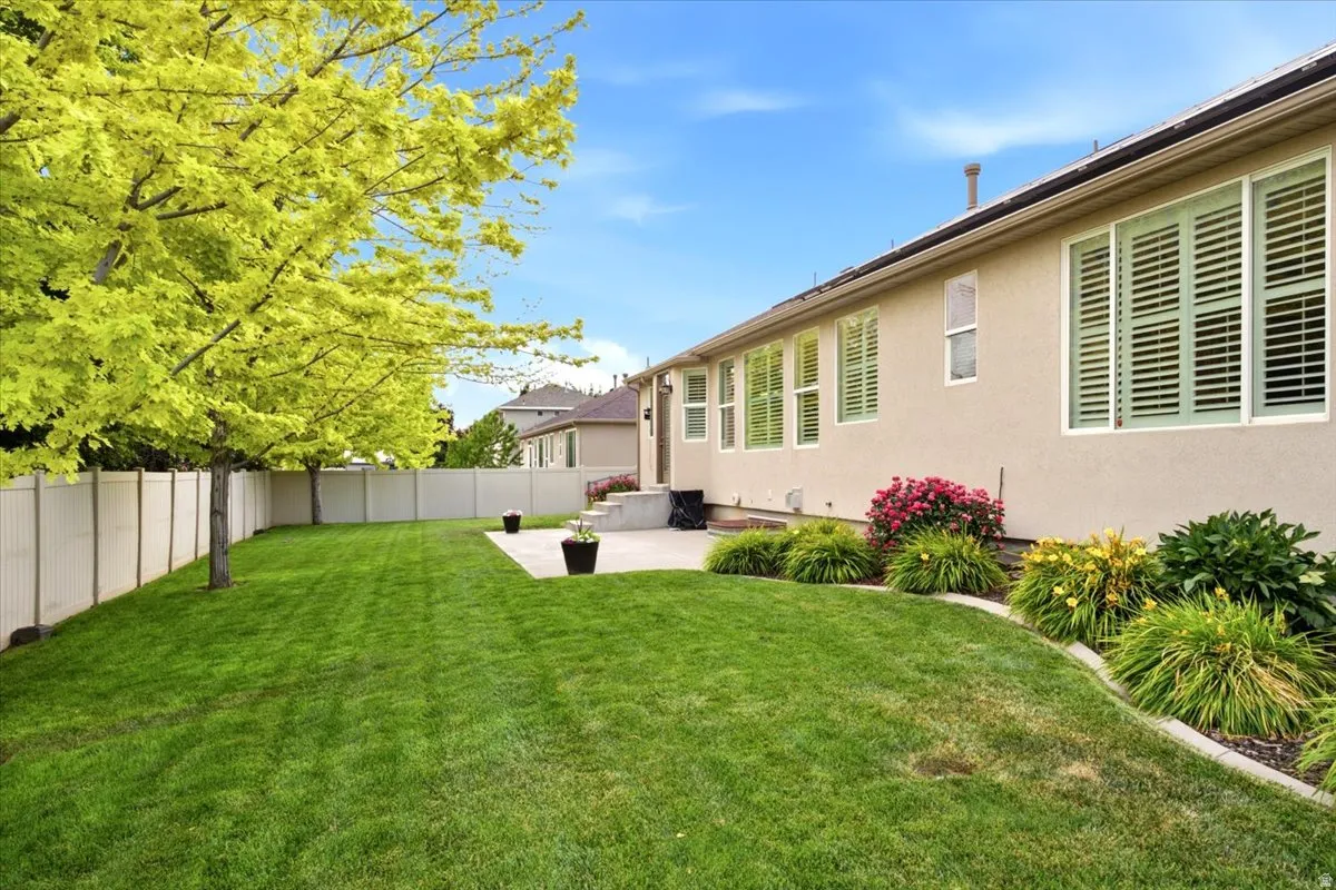 Spacious backyard featuring a lush lawn, mature trees, and a privacy fence