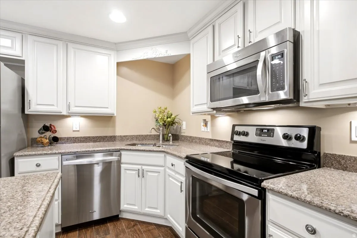 Kitchen featuring white cabinetry with crown molding, granite-finish countertops, and stainless steel appliances