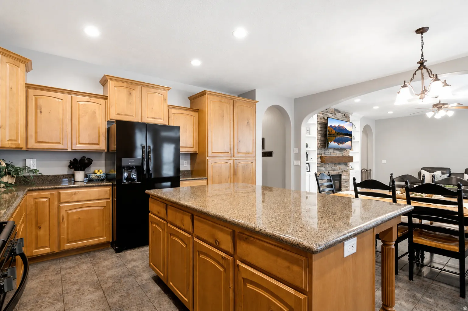 Kitchen featuring a large central island with a stone-finish countertop, light wood cabinetry, recessed lighting, and tile flooring