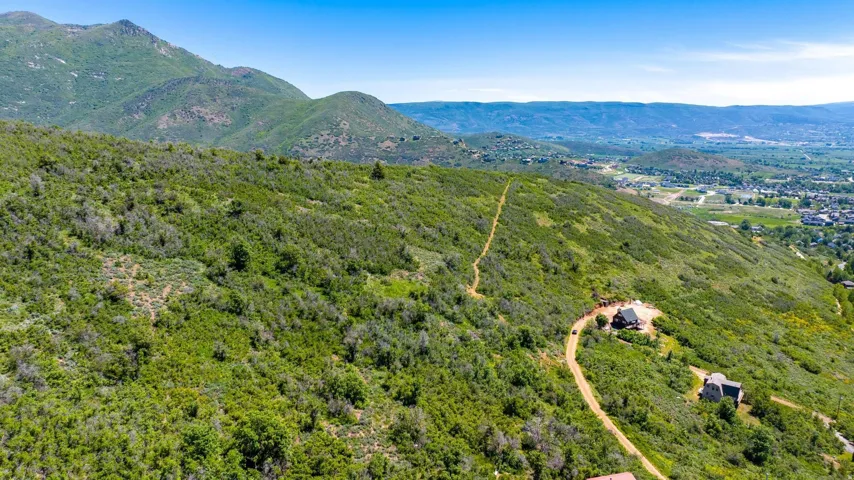 Expansive mountain landscape featuring verdant hillsides and distant residential areas