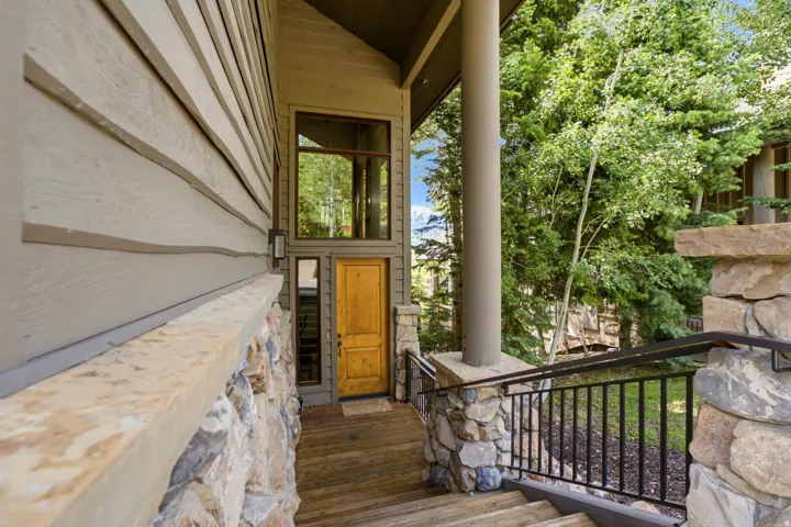 Stone and wood-finish siding exterior featuring a prominent wood entry door