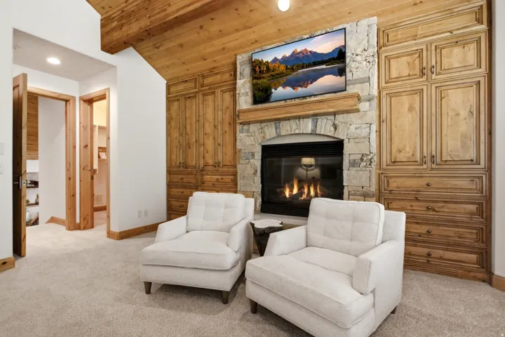 Stone-clad fireplace with a built-in media center, wood-finish ceiling, and integrated lighting