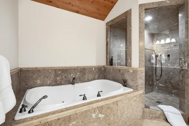 Soaking tub with dark bronze fixtures, set within a natural stone surround