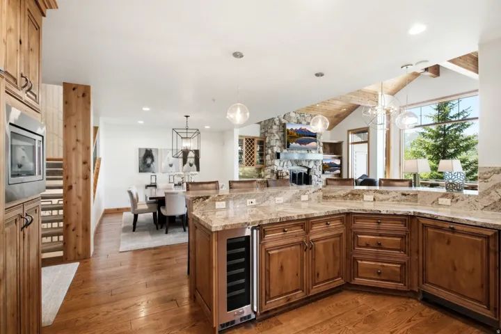 Kitchen featuring wood cabinetry, stone countertops, a built-in wine cooler, and hardwood flooring