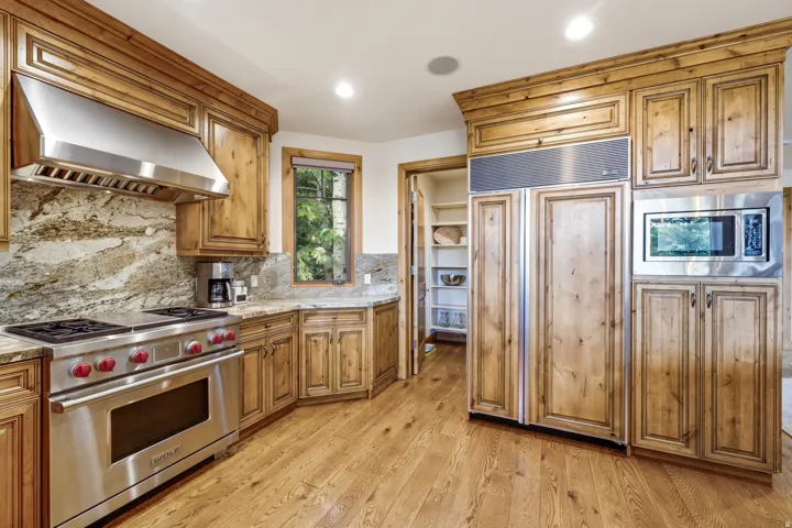 Kitchen featuring knotty wood cabinetry, granite countertops, stainless steel appliances, and wood-finish flooring