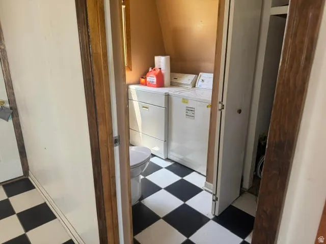Compact utility space featuring a toilet, washer, and dryer