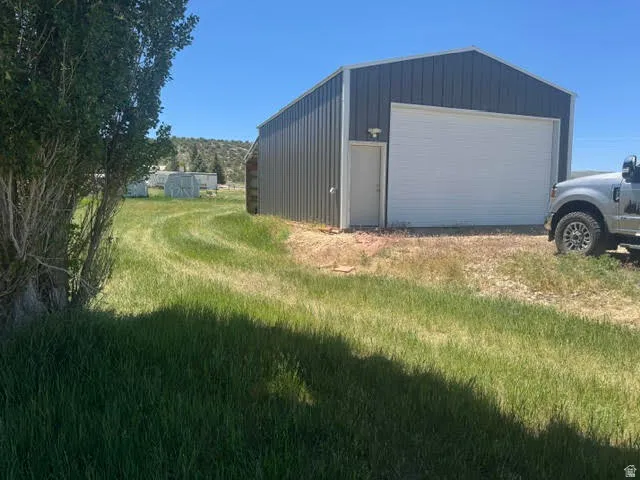 Metal outbuilding featuring a white overhead door, a pedestrian door, and an exterior light fixture