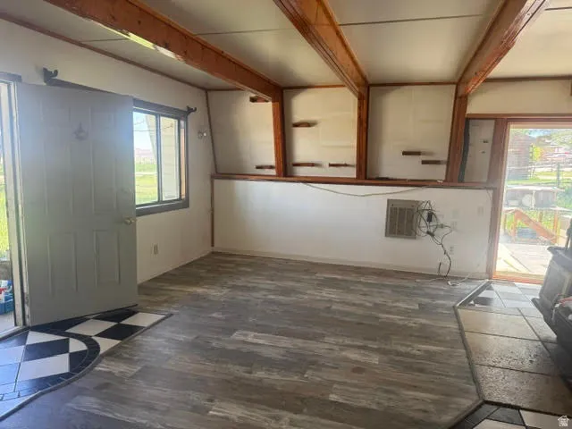 Interior living space featuring exposed wood beams, wood-finish flooring, and a sliding glass door