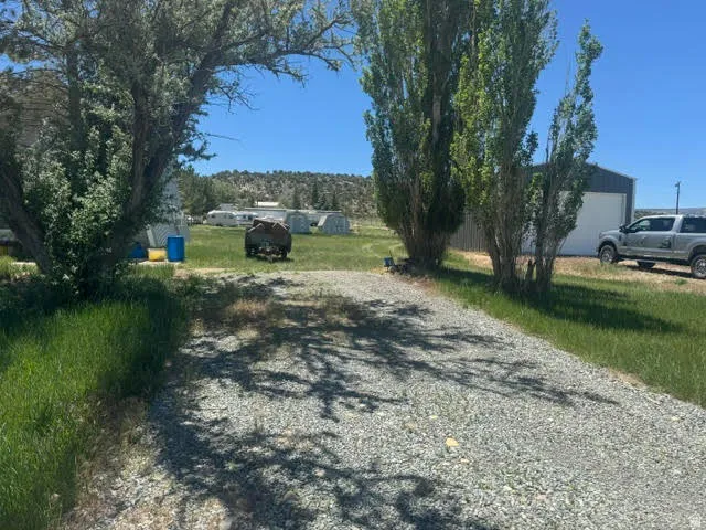 Gravel driveway providing access to a metal-sided building with a white overhead door