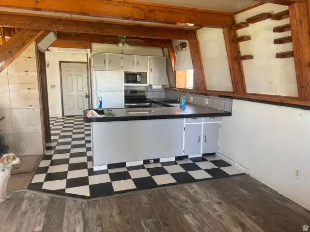 Kitchen featuring a black and white checkered floor, an island with countertop and integrated sink, light gray cabinetry, and a tile backsplash