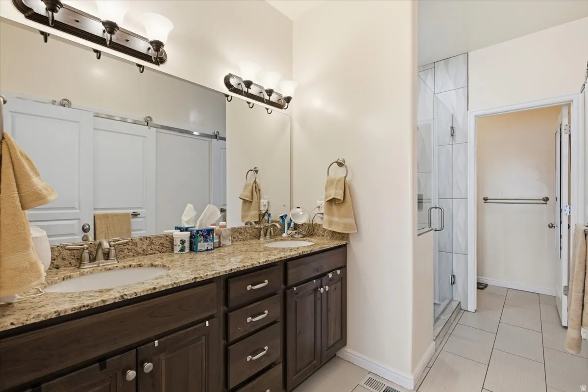 Bathroom featuring a double vanity with stone-finish countertop and dark wood cabinetry