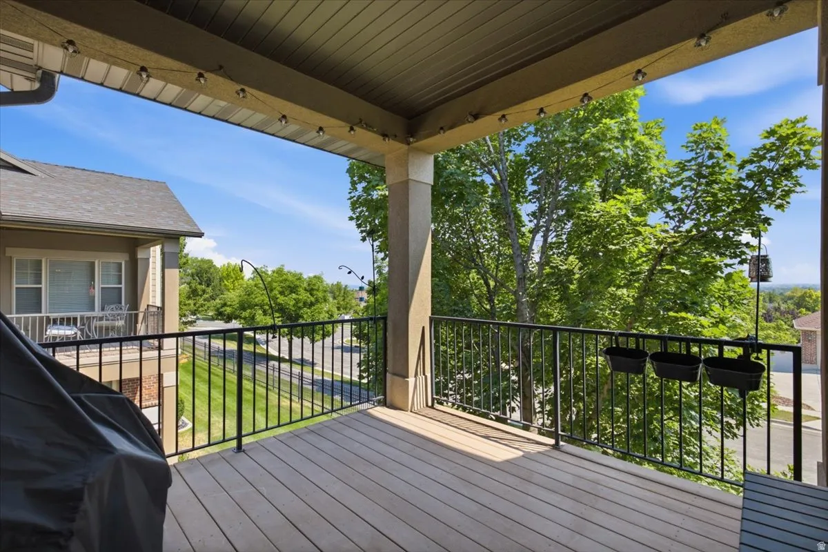 Spacious exterior deck featuring composite decking, a black metal railing, and an overhead string lighting fixture