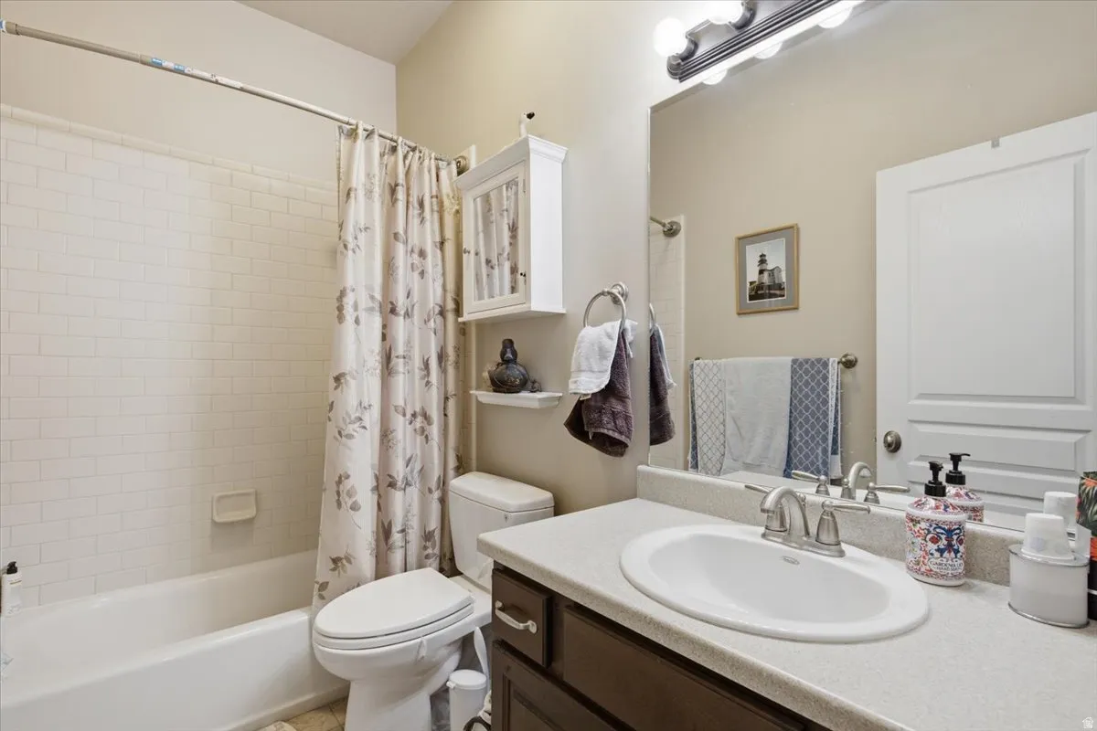 Bathroom featuring a white subway tile tub surround, white vanity cabinet with an integrated sink, and a large wall-mounted mirror
