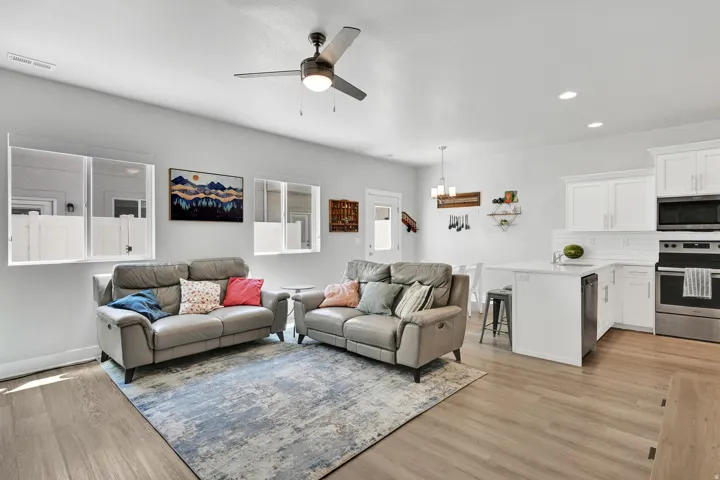 Open-concept living space with wood-finish flooring, a contemporary ceiling fan, and recessed lighting