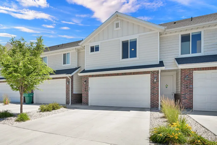 Townhome exterior featuring light-colored siding, brick accents, and a composition shingle roof