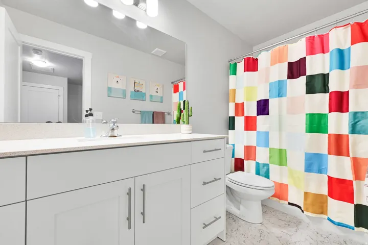 Contemporary bathroom featuring a light gray vanity with ample storage, a solid surface countertop, an undermount sink, and a large mirror