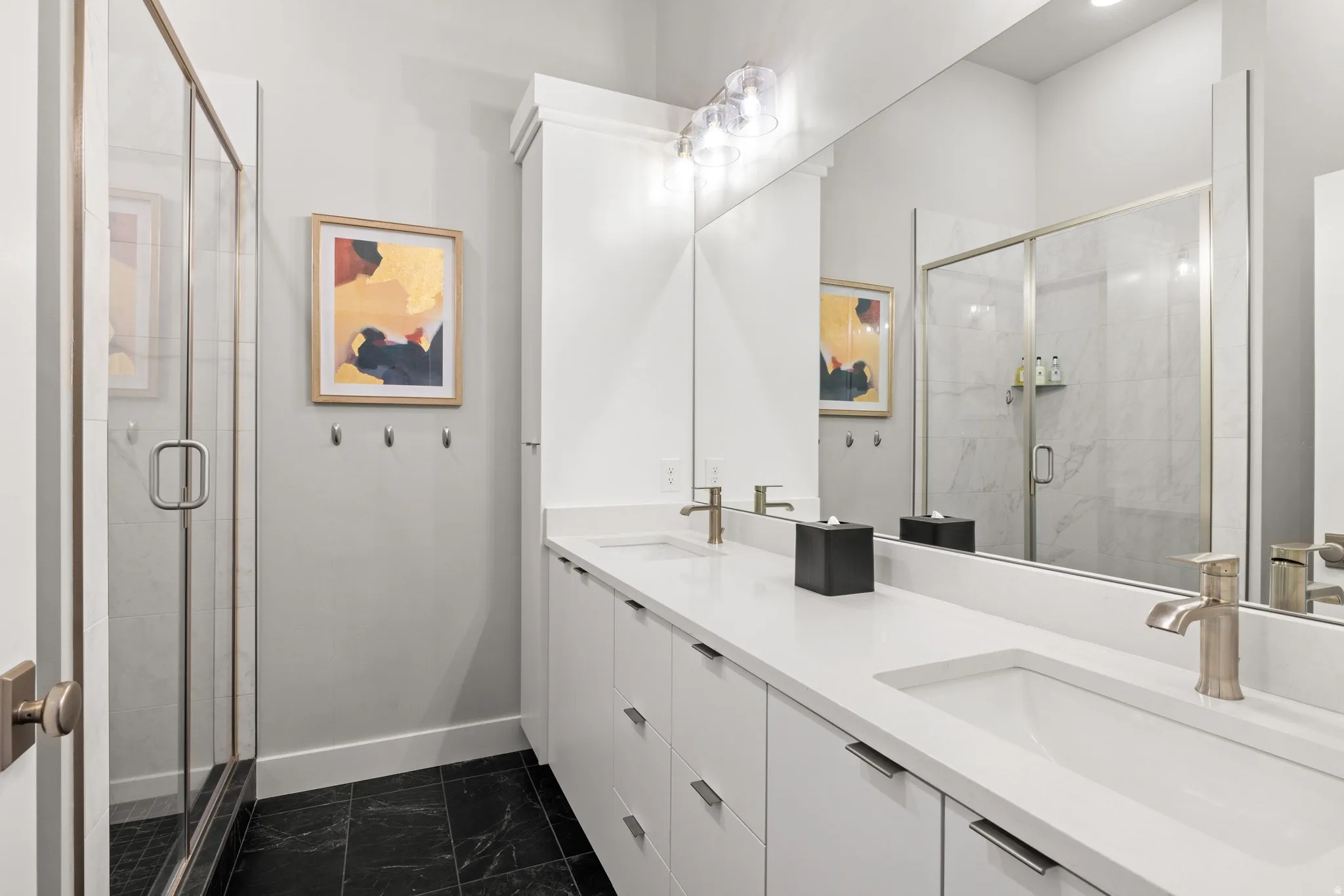 Double vanity featuring white cabinetry, integrated sinks, brushed nickel fixtures, and a spacious mirror