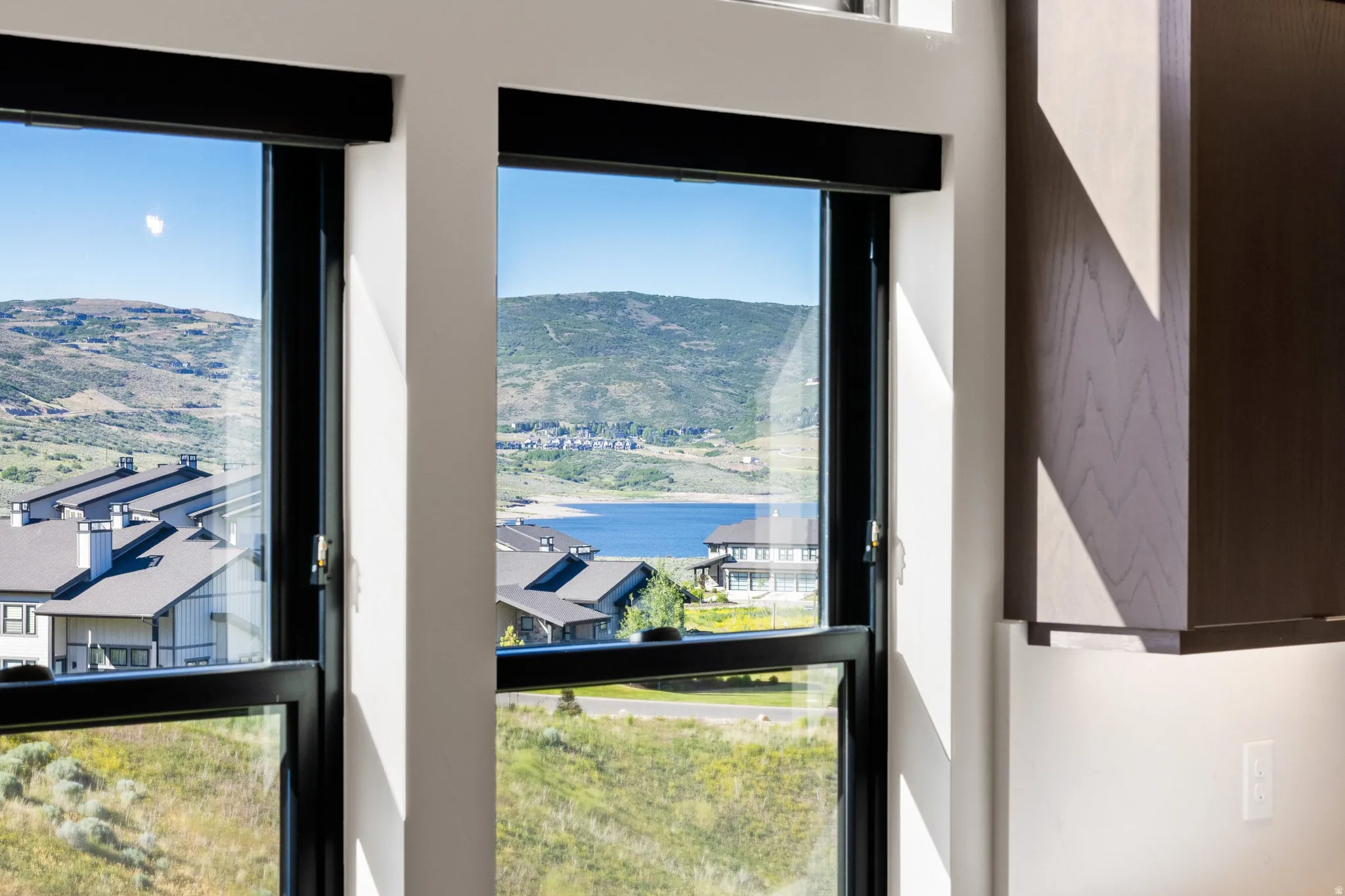 Framed mountain and lake scenery through multiple large windows with black sills