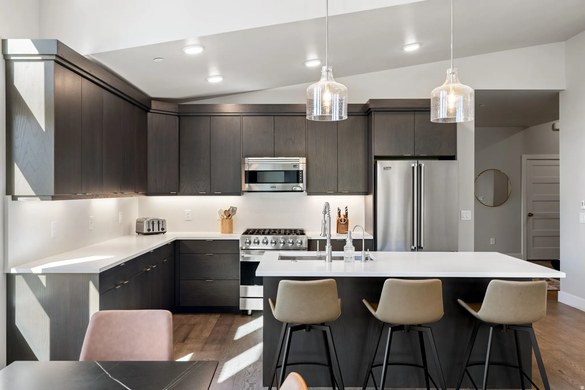 Contemporary kitchen featuring dark wood-finish cabinetry, stainless steel appliances, and white countertops