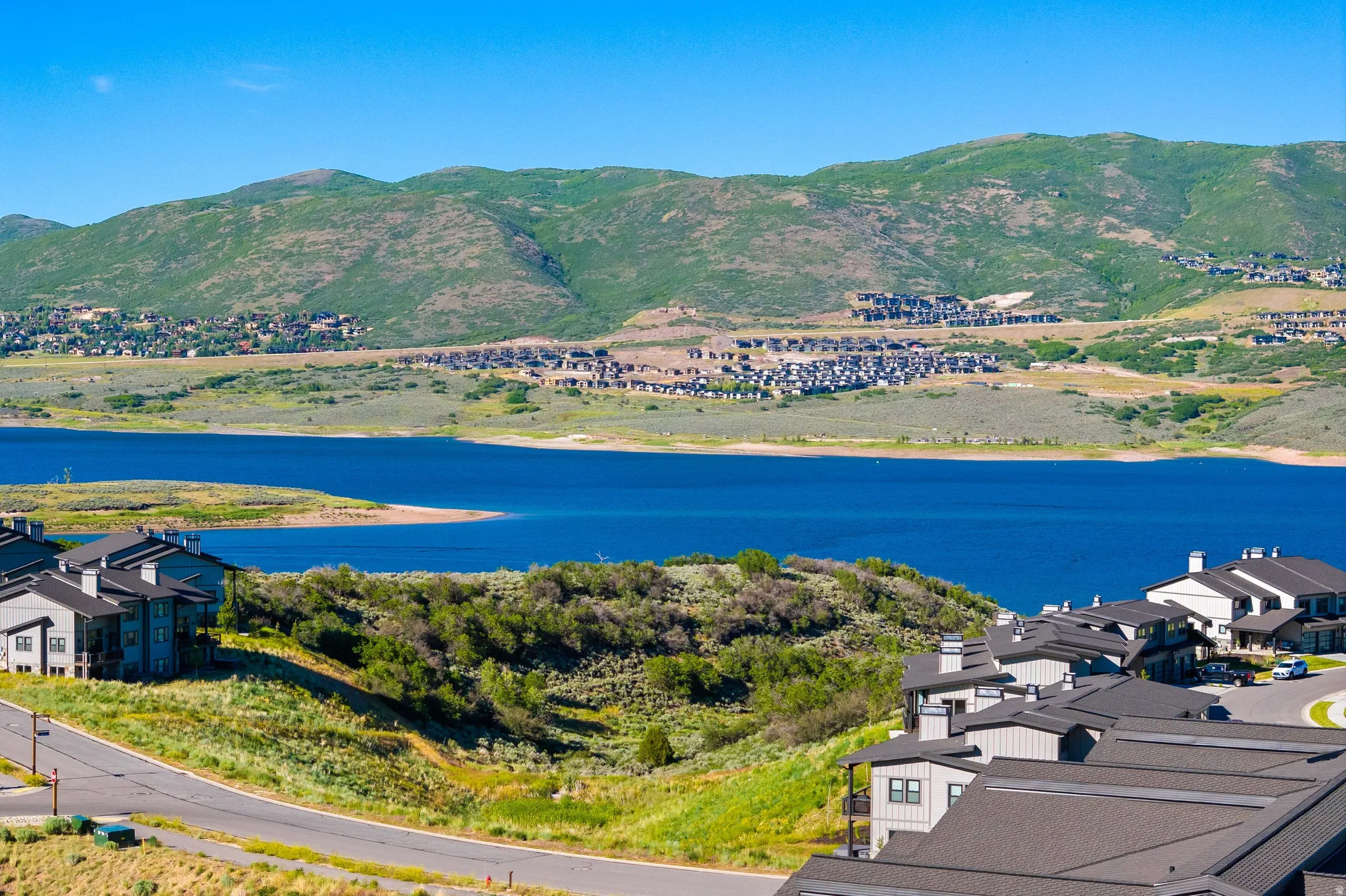 Expansive lake and mountain scenery featuring contemporary residential architecture with dark roofs