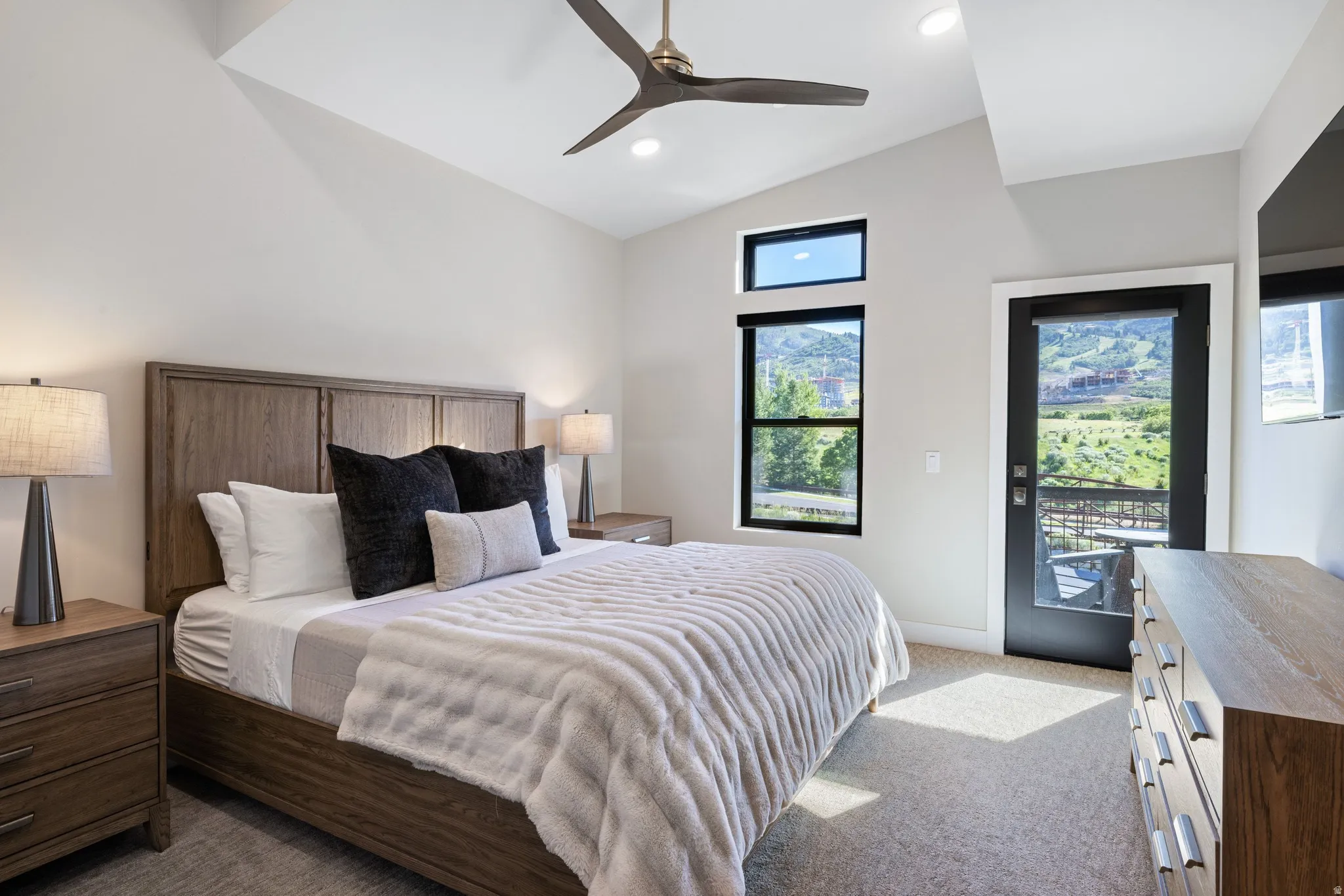 Vaulted ceiling bedroom featuring a contemporary ceiling fan, recessed lighting, and a private glass-paneled door leading to an outdoor space