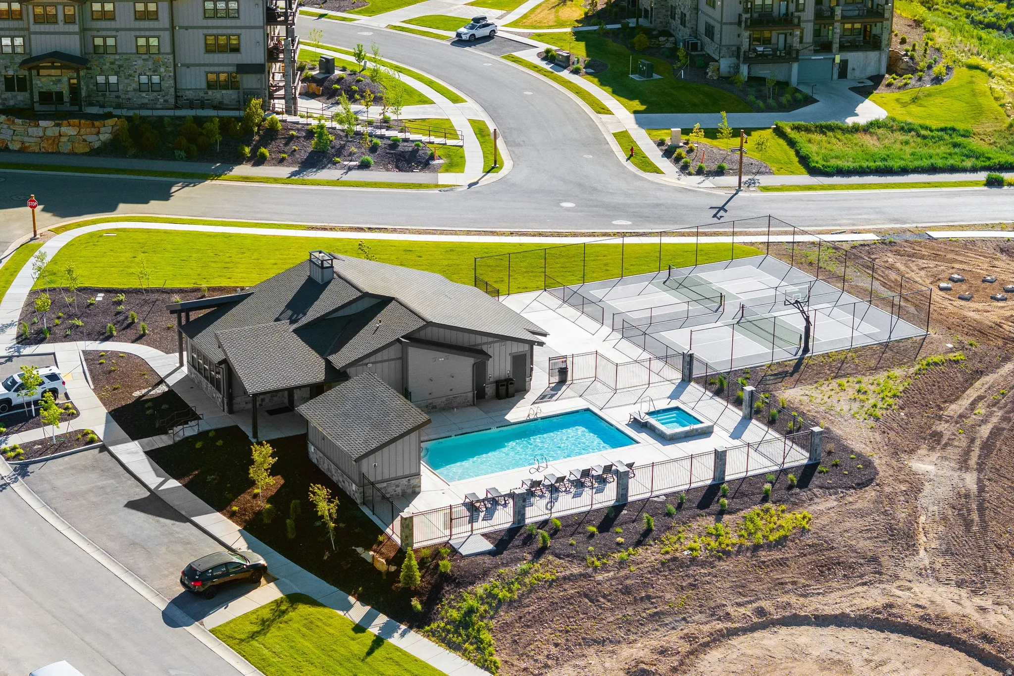 Community amenity center featuring a swimming pool, hot tub, and fenced sports courts