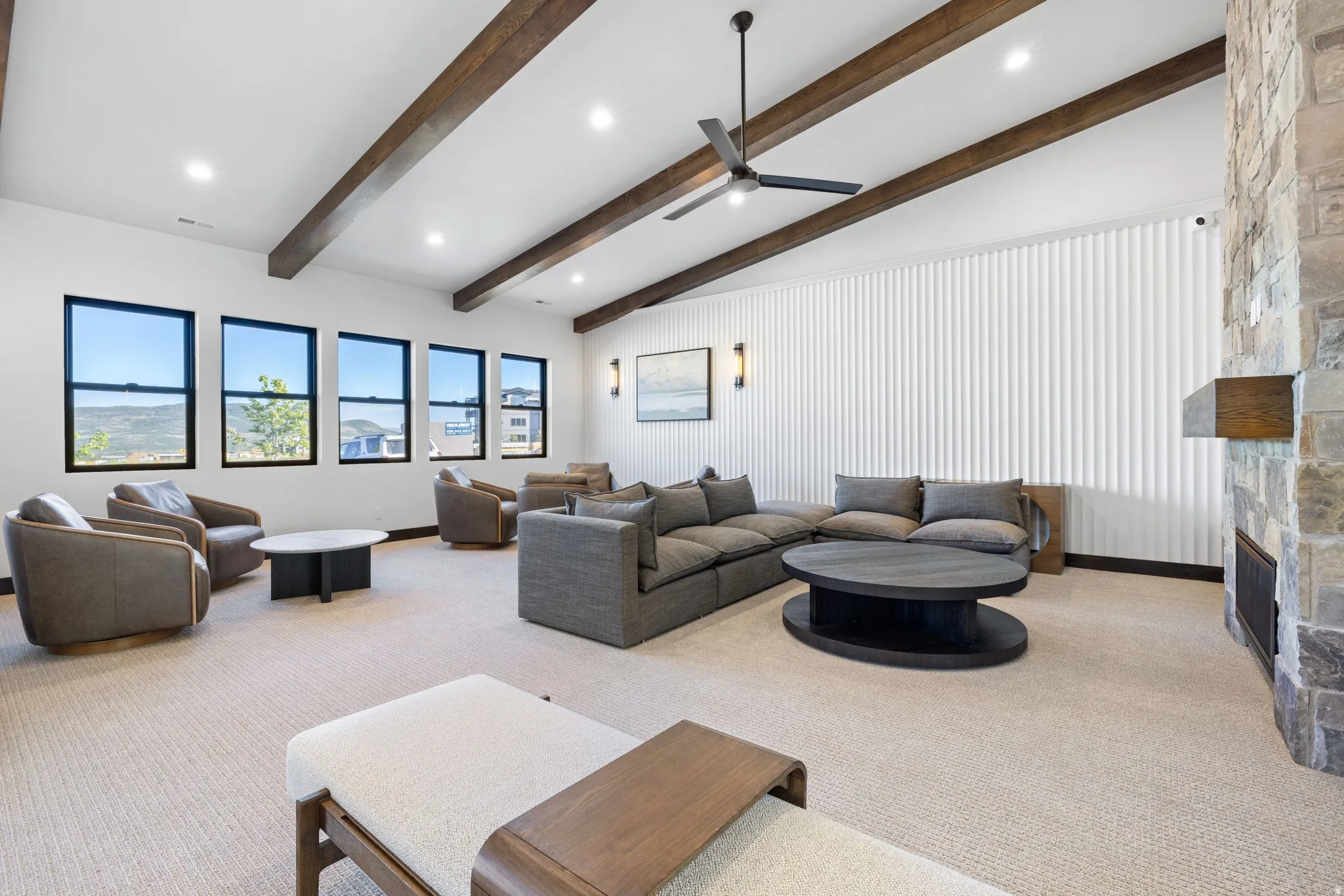 Spacious room featuring a vaulted ceiling with exposed wood beams and a contemporary ceiling fan