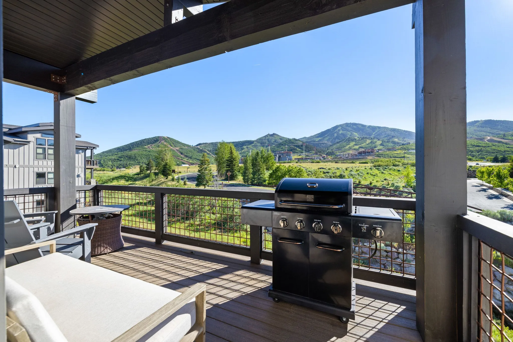 Expansive outdoor deck featuring composite wood-finish flooring, dark wood-tone support beams, and a metal railing