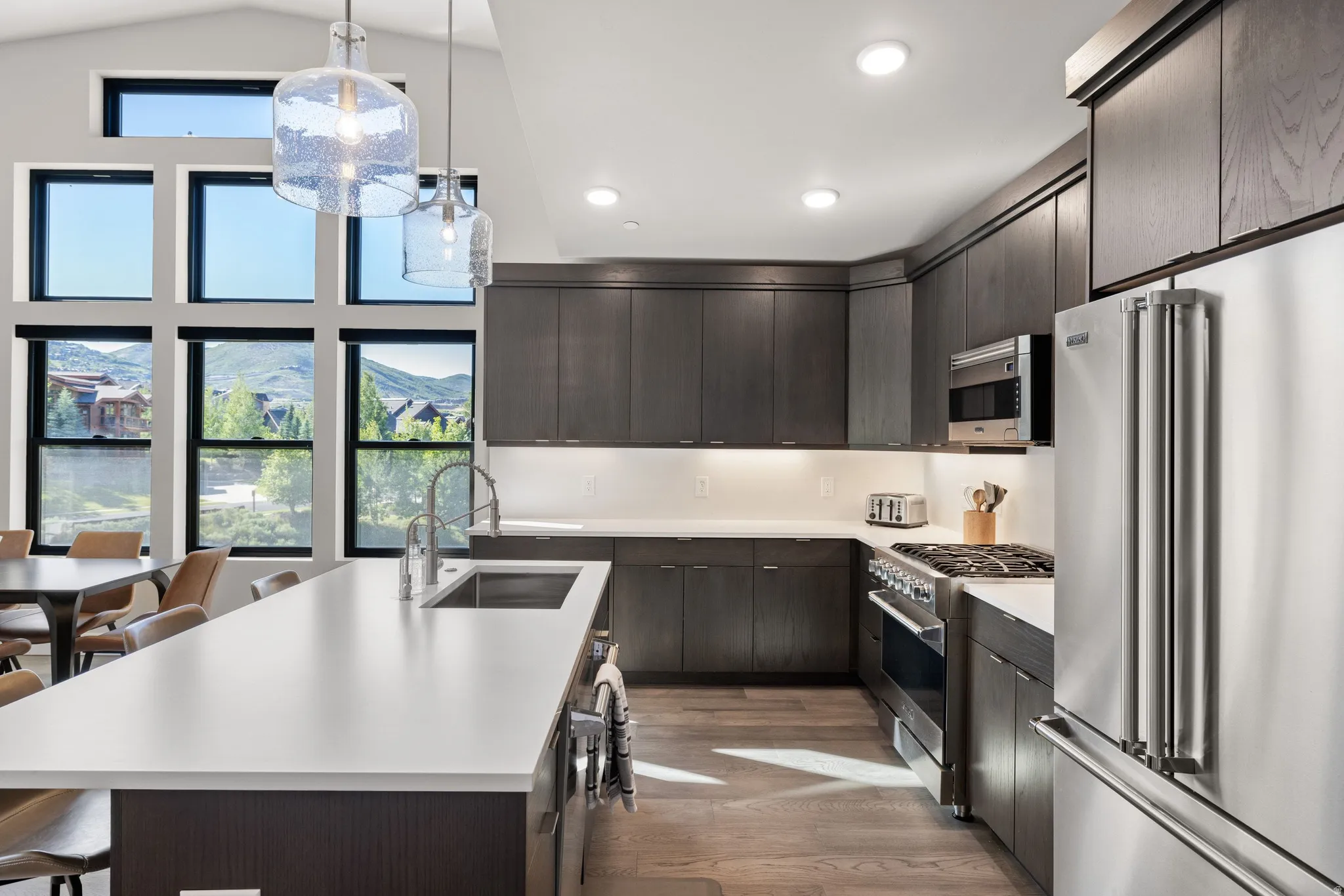 Modern kitchen featuring dark wood-finish cabinetry, stainless steel appliances, and light countertops