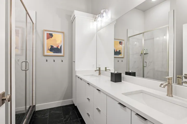 Double vanity featuring white cabinetry, integrated sinks, brushed nickel fixtures, and a spacious mirror