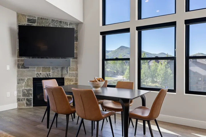 Spacious room featuring a stone-faced fireplace with a wood mantle, a mounted flat-screen television, and expansive windows