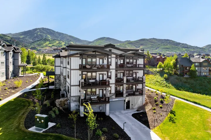 Multi-story building featuring white horizontal siding and dark trim with stone accents