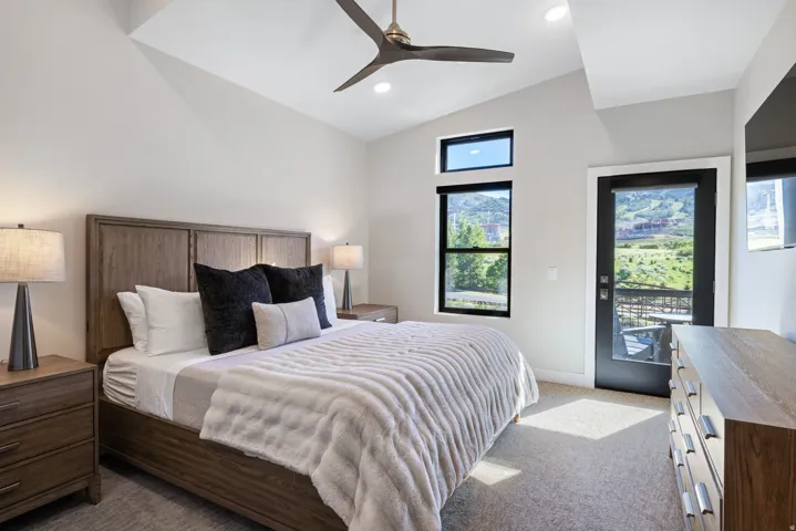 Vaulted ceiling bedroom featuring a contemporary ceiling fan, recessed lighting, and a private glass-paneled door leading to an outdoor space