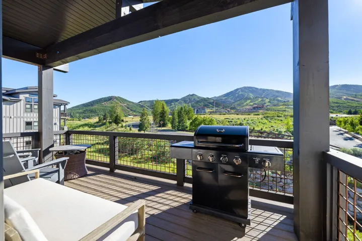 Expansive outdoor deck featuring composite wood-finish flooring, dark wood-tone support beams, and a metal railing