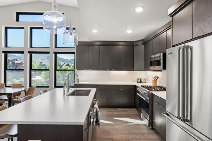 Modern kitchen featuring dark wood-finish cabinetry, stainless steel appliances, and light countertops