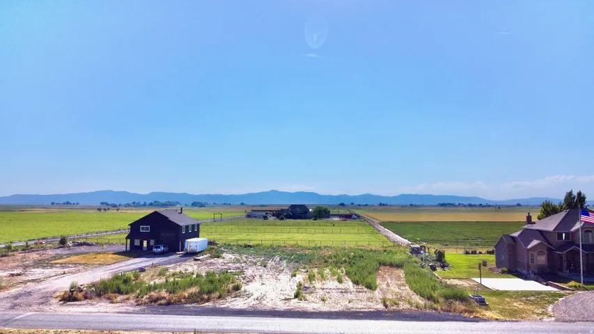 Expansive acreage featuring a dark-toned two-story residence, long driveway, and surrounding green fields