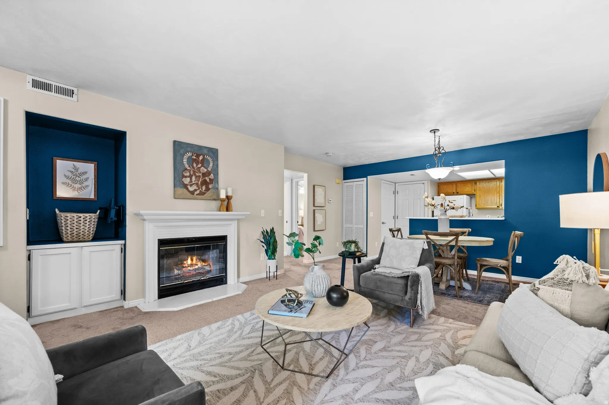 Living area featuring a white mantel gas fireplace, a built-in media niche with lower cabinetry, and carpeted flooring