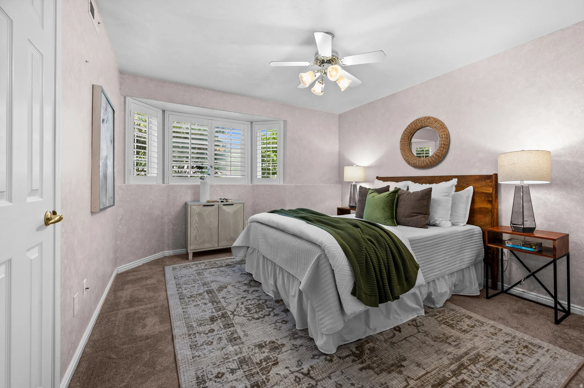 Bedroom featuring a bay window with plantation shutters, a ceiling fan with integrated lighting, and textured wall finishes