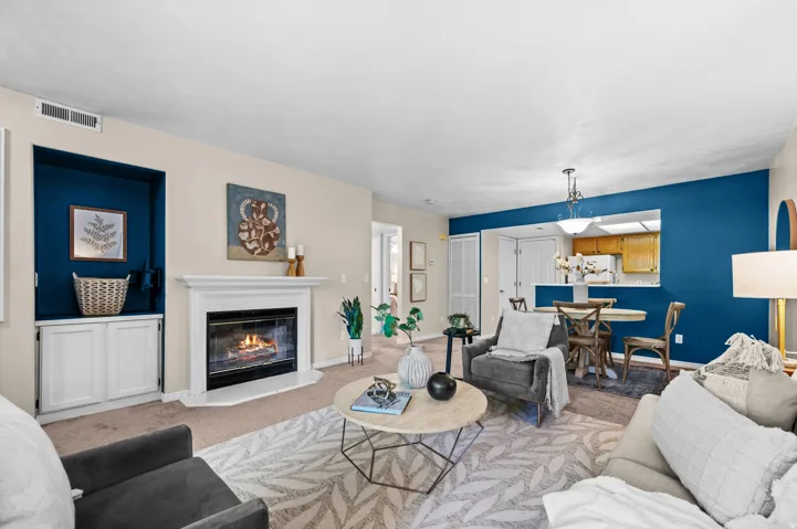 Living area featuring a white mantel gas fireplace, a built-in media niche with lower cabinetry, and carpeted flooring