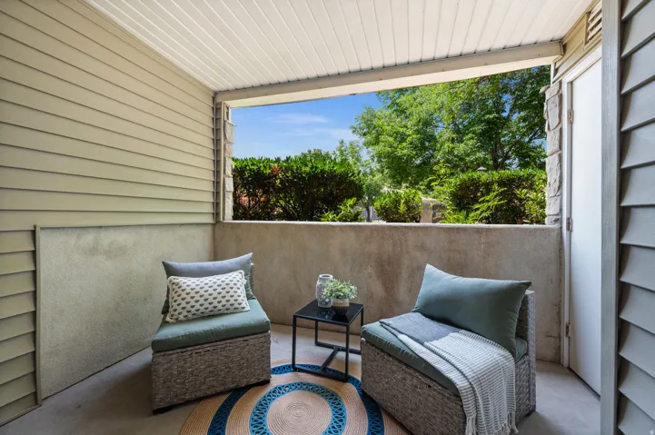 Covered outdoor patio featuring beige horizontal siding and a concrete half-wall